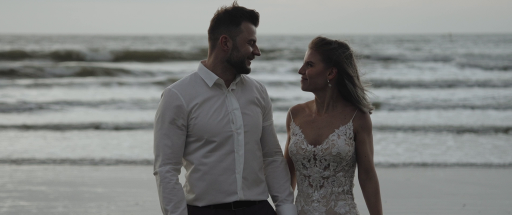 Nicole & Daniel stehen am Strand von Hoek van Holland und schauen sich beim Sonnenuntergang tief in die Augen.